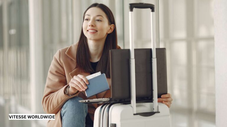 Traveler holding passport next to suitcase and laptop